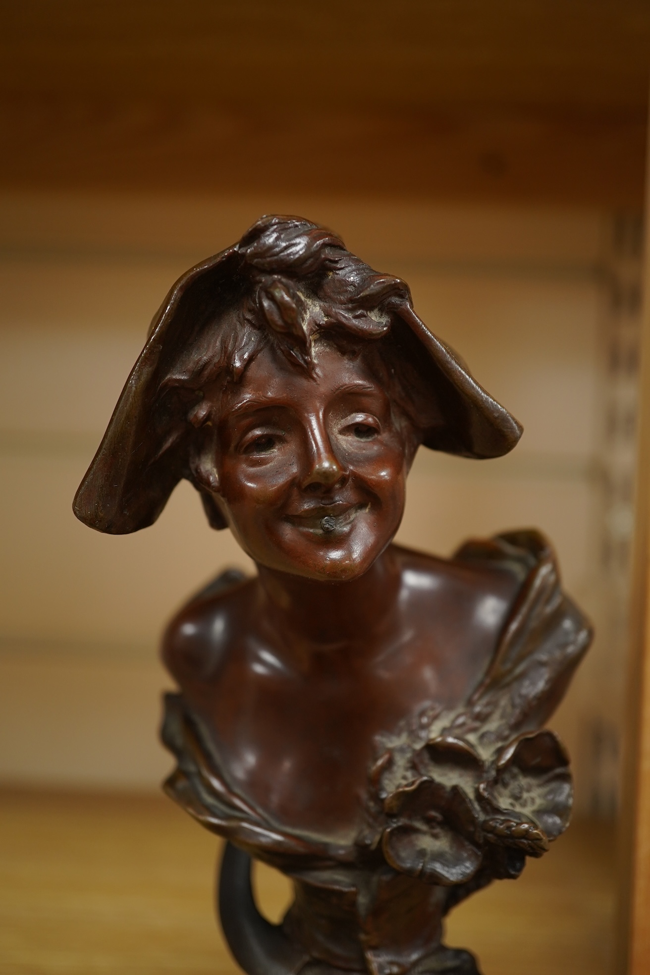 A late 19th century bronze bust of a lady in a hat with floral decoration , mounted on marble, signed, 21.5cm high.